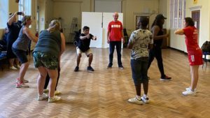 A group of young people participating in a dance session lead by a sports coach