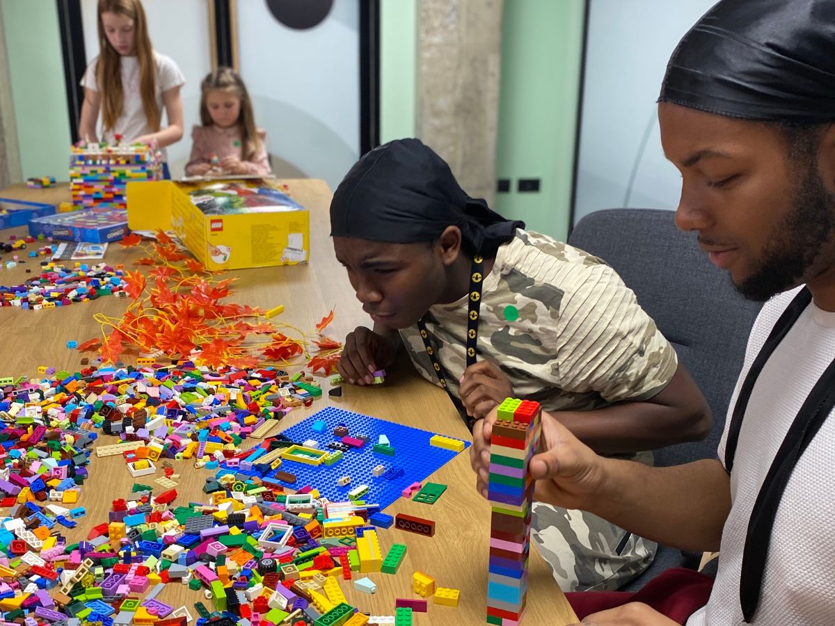 People sitting around a table full of colourful Lego