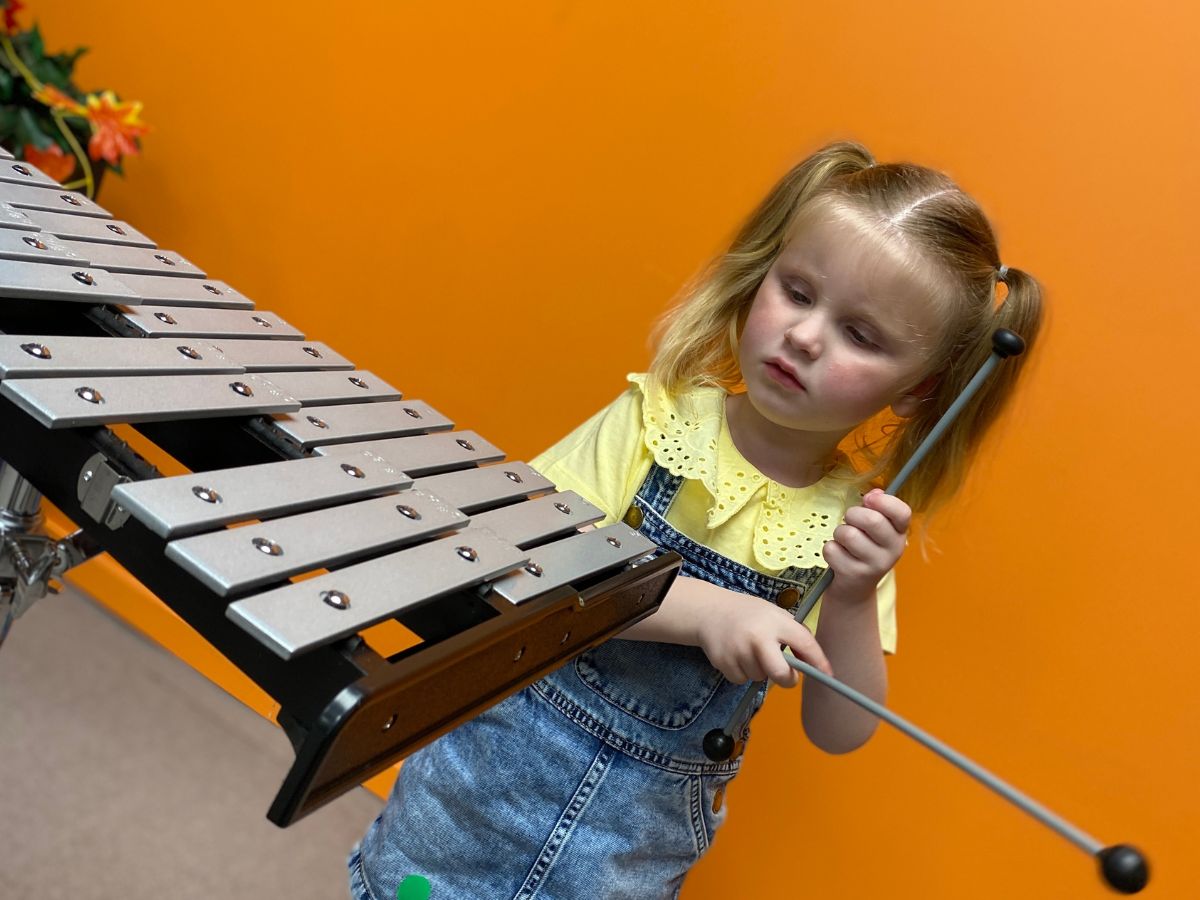 A little girl playing a xylophone