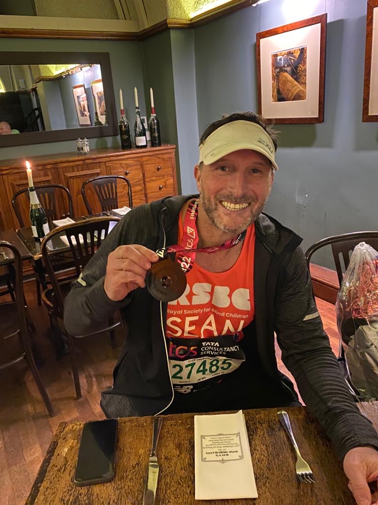 A man smiling and showing his medal