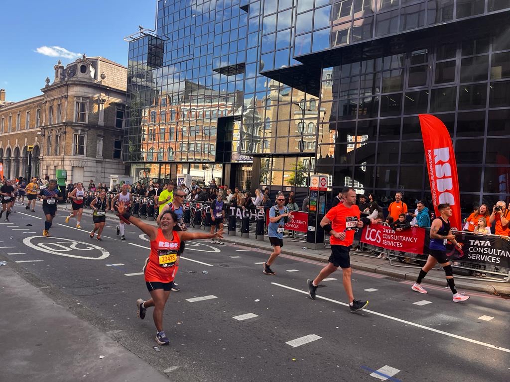 A woman running at the London Marathon passing the RSBC Cheer point