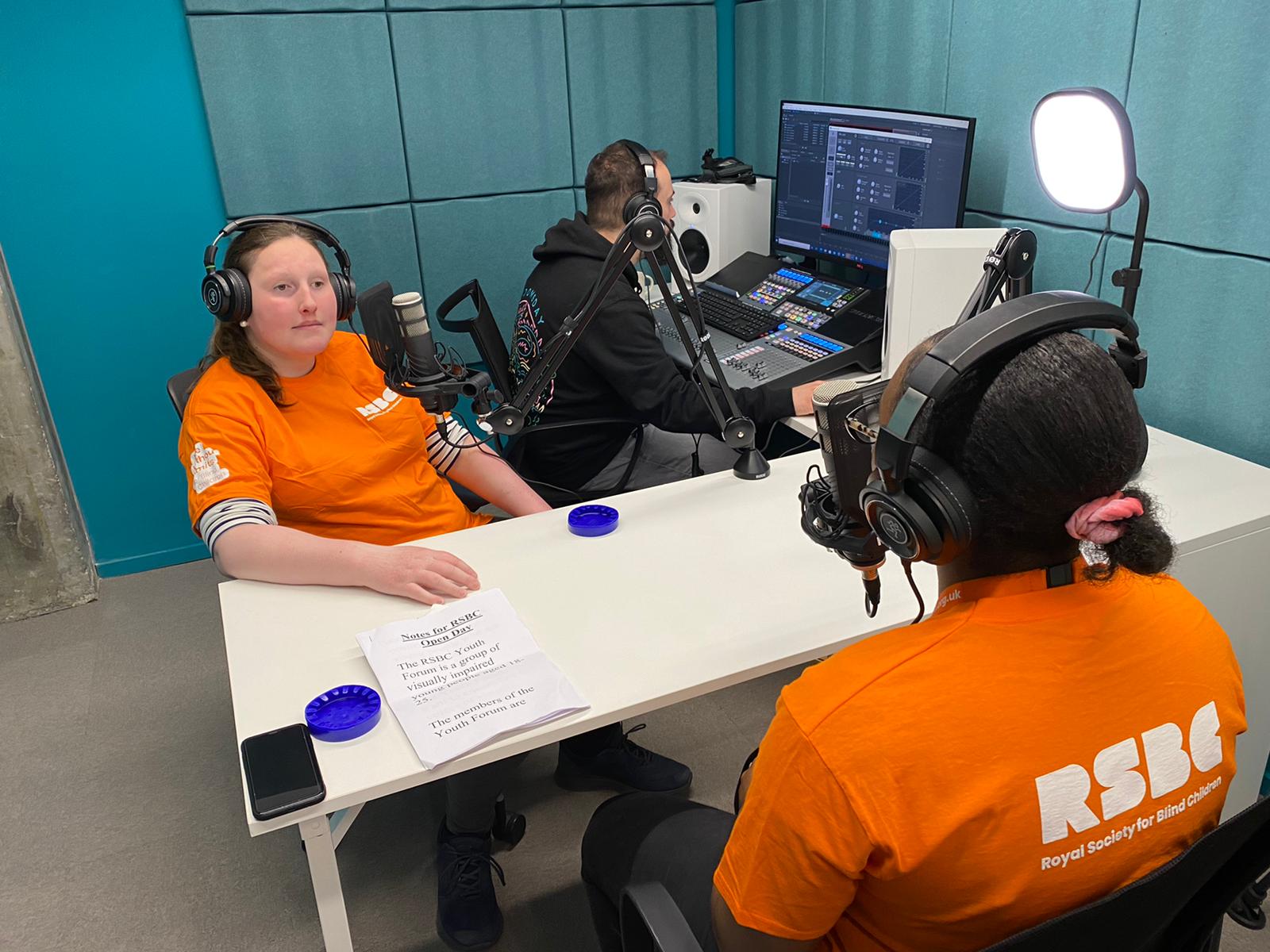 Three people recording a podcast in a media room