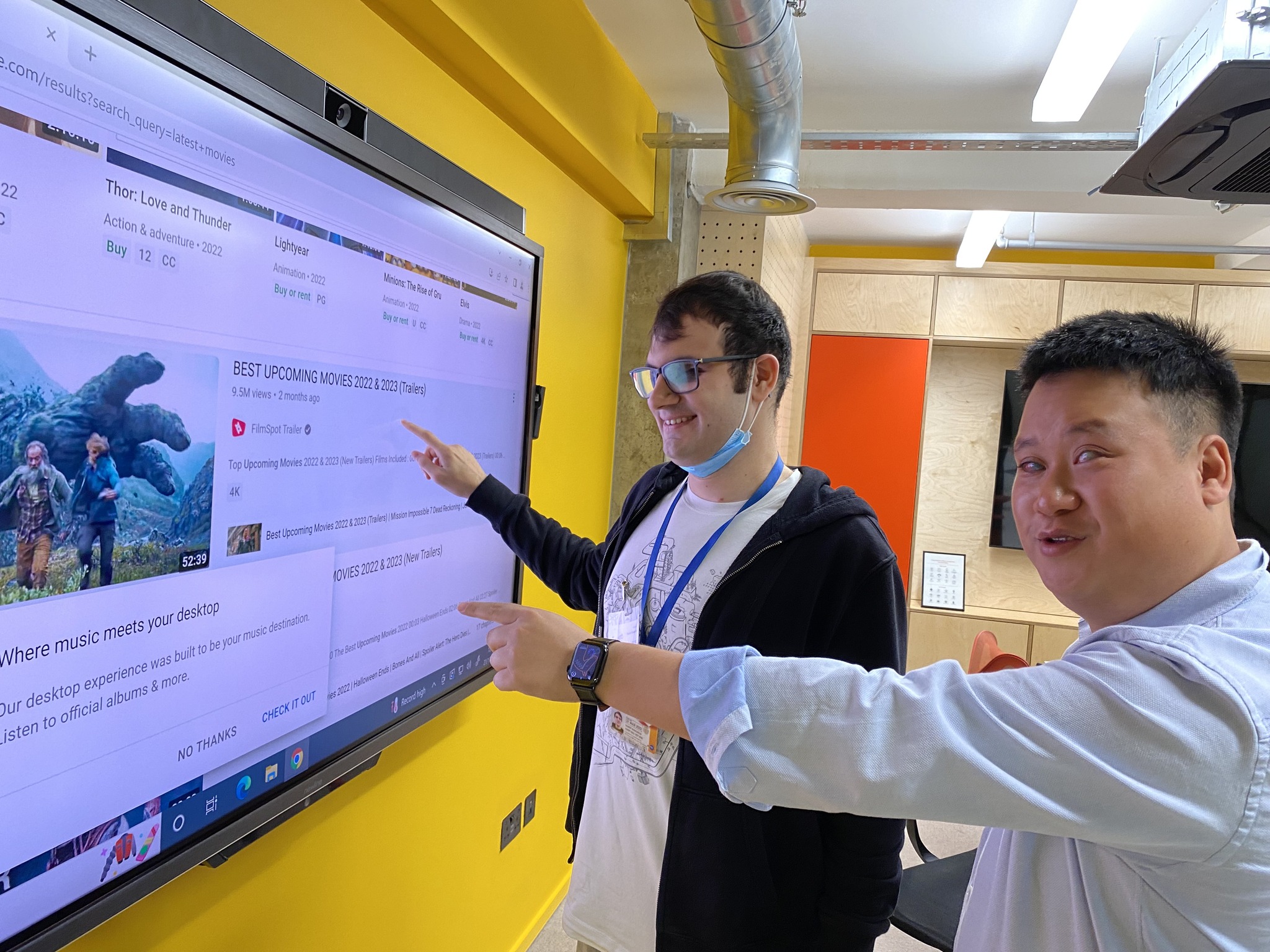 2 people looking at a big tactile screen on a wall