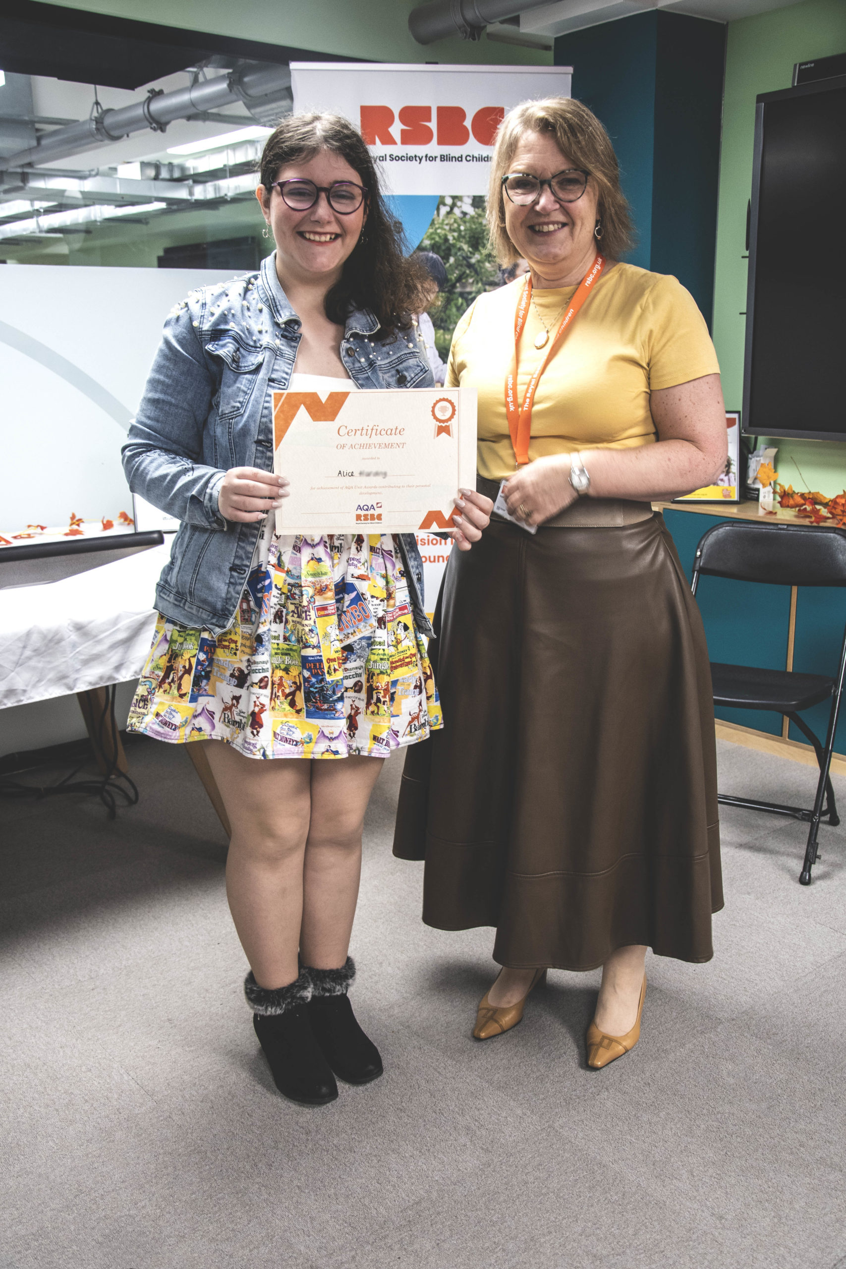 A young woman receiving a certificate standing up next a woman