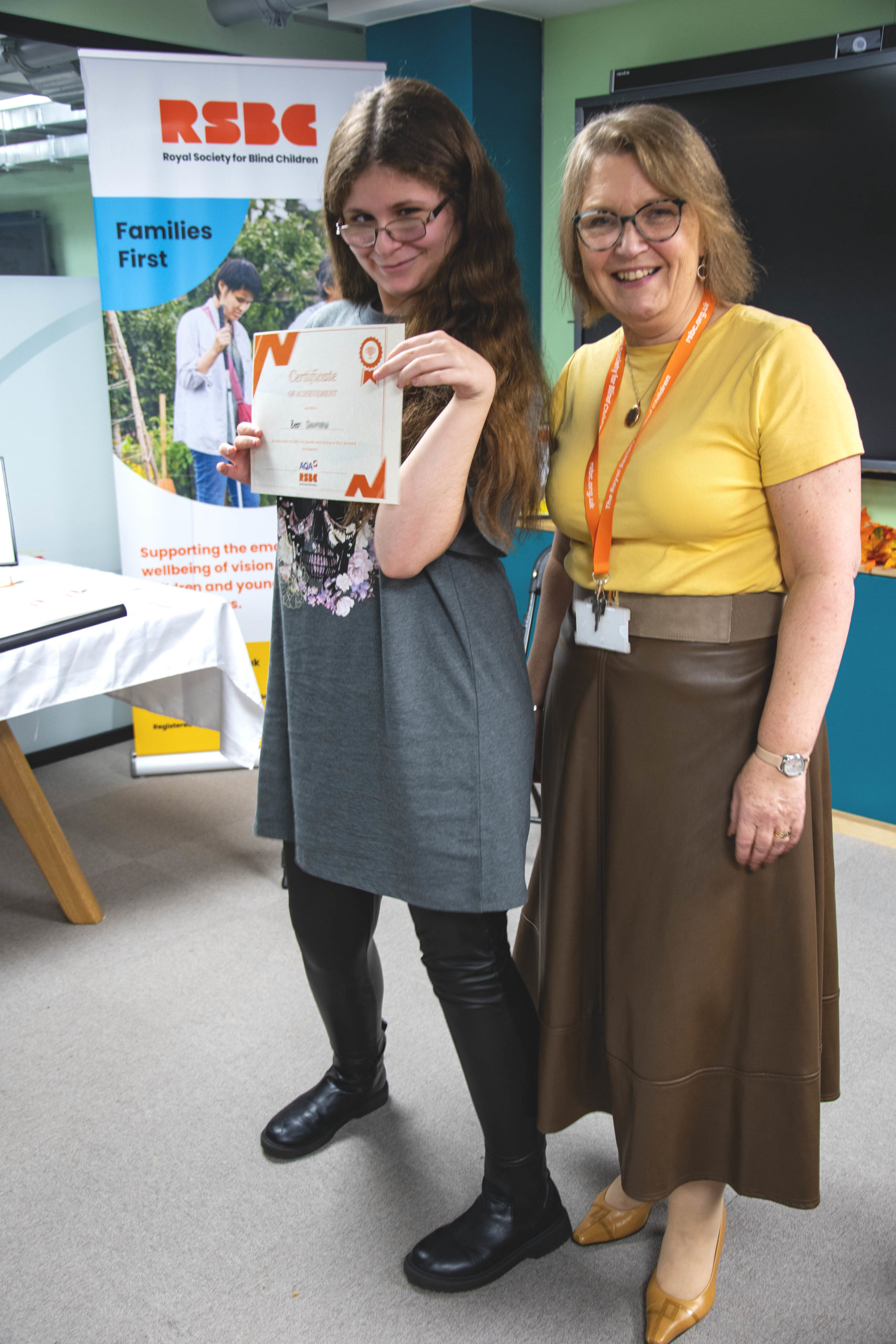 A young woman receiving a certificate standing up next a woman