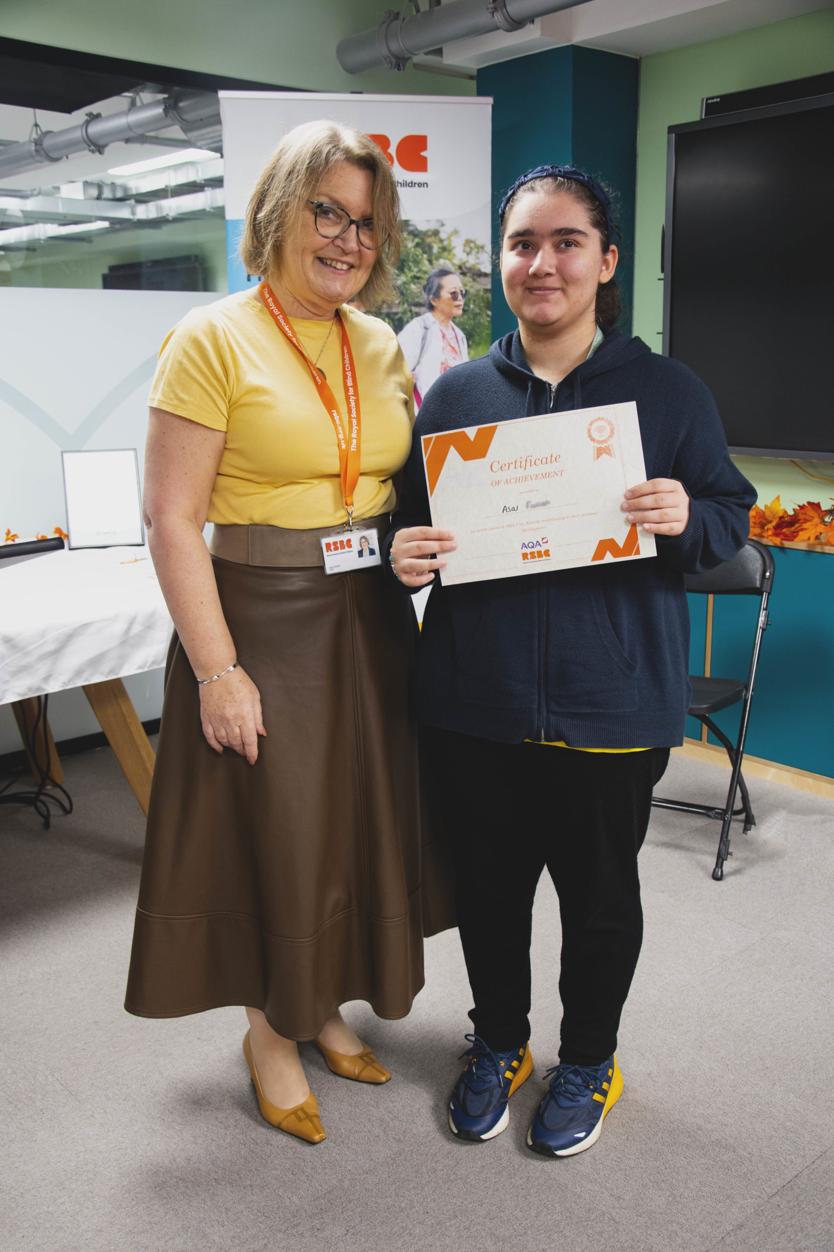 A young woman receiving a certificate standing up next a woman