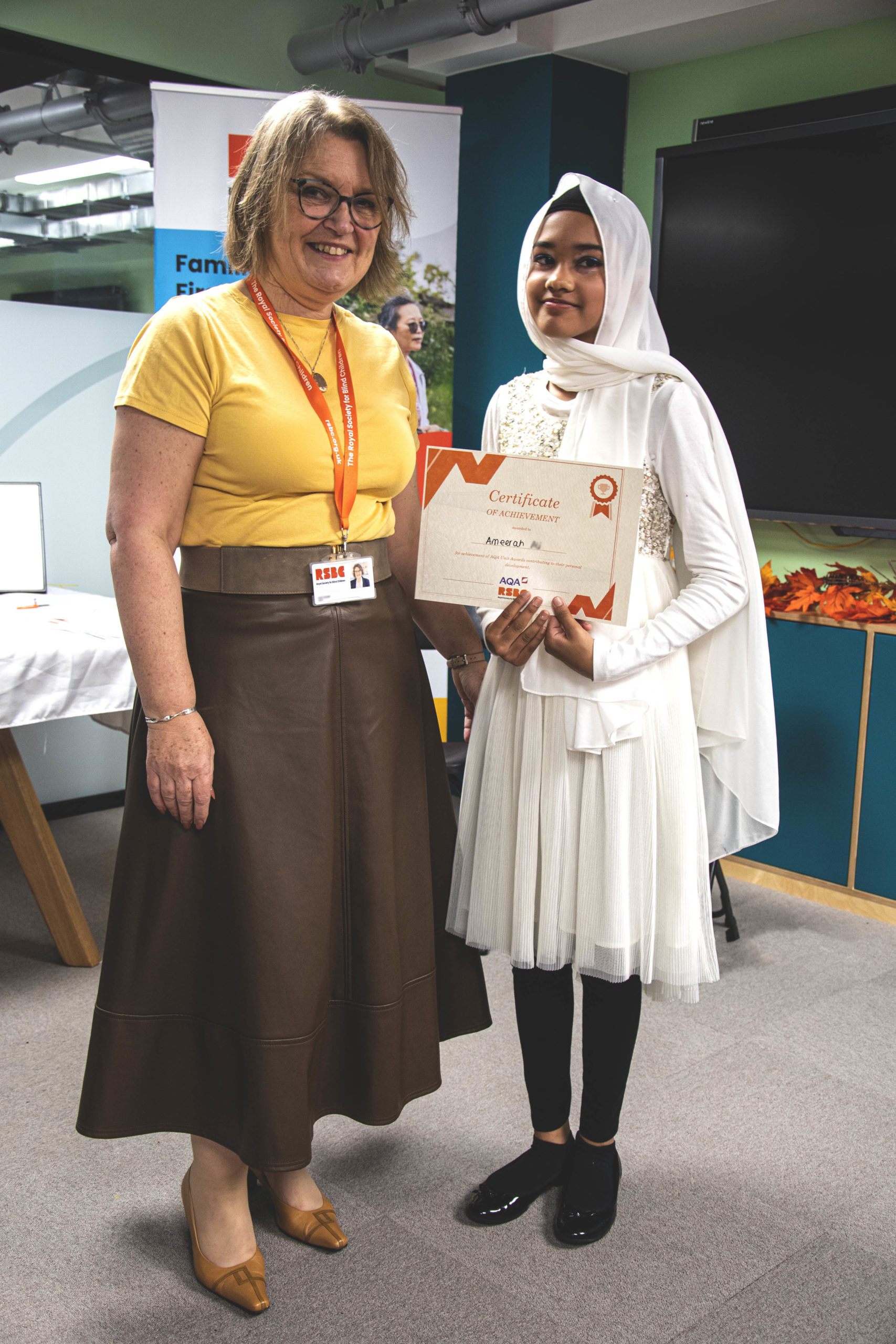 A young woman receiving a certificate standing up next a woman