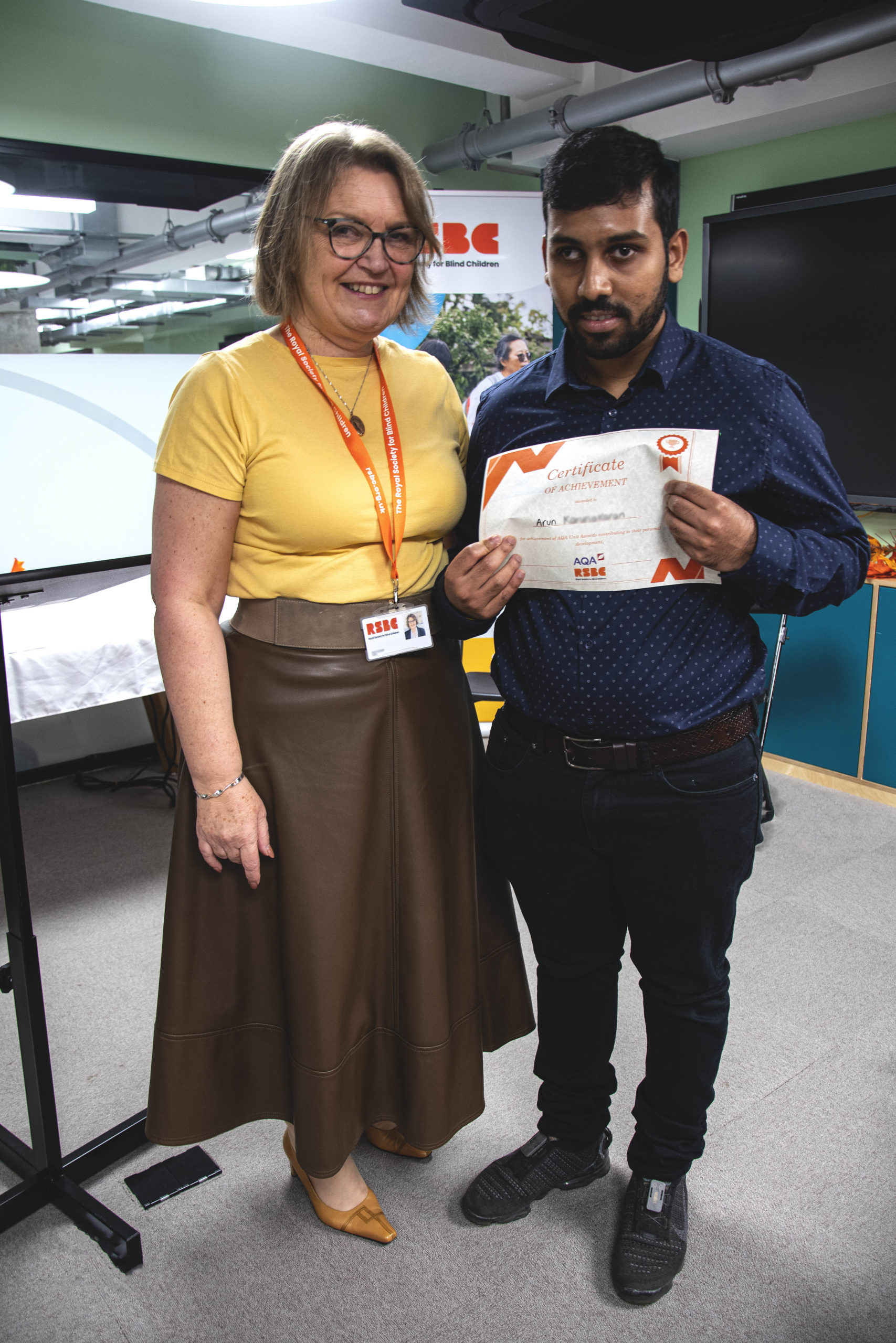 A young man receiving a certificate standing up next a woman