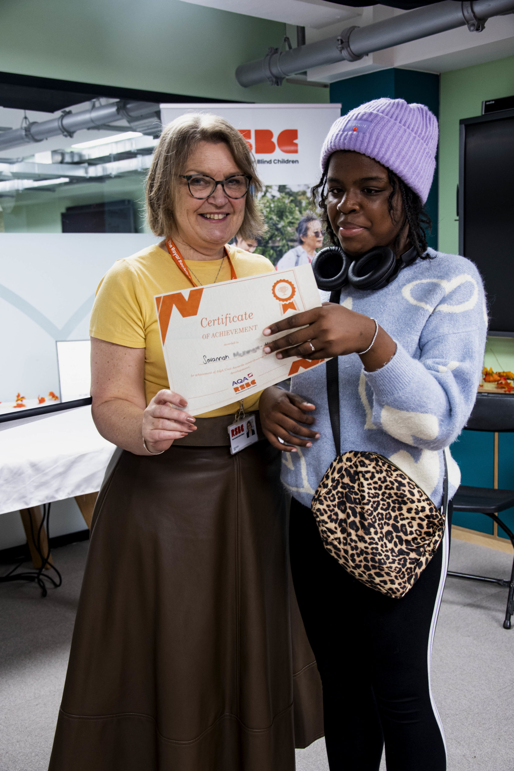 A young woman receiving a certificate standing up next a woman