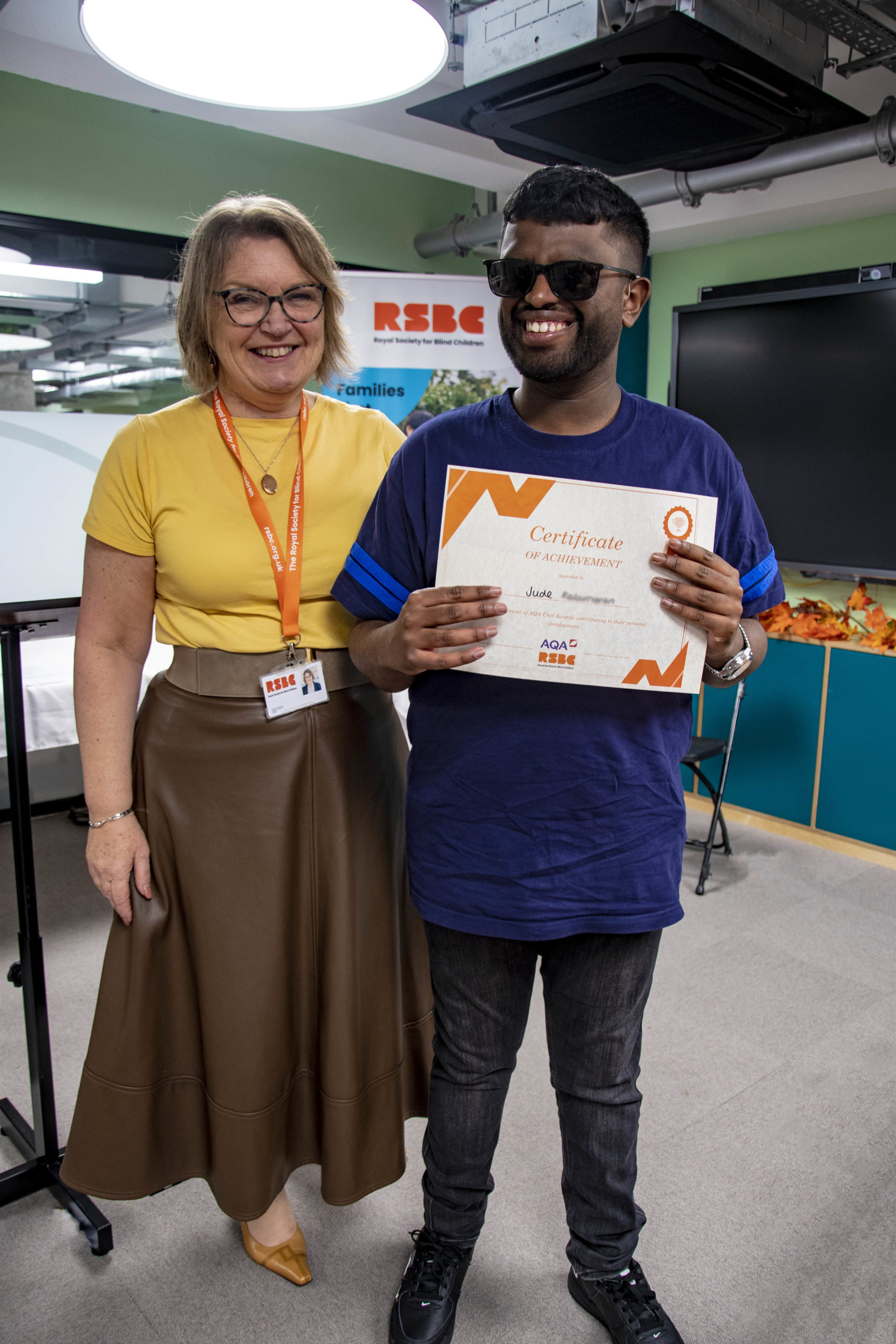 A young man receiving a certificate standing up next a woman