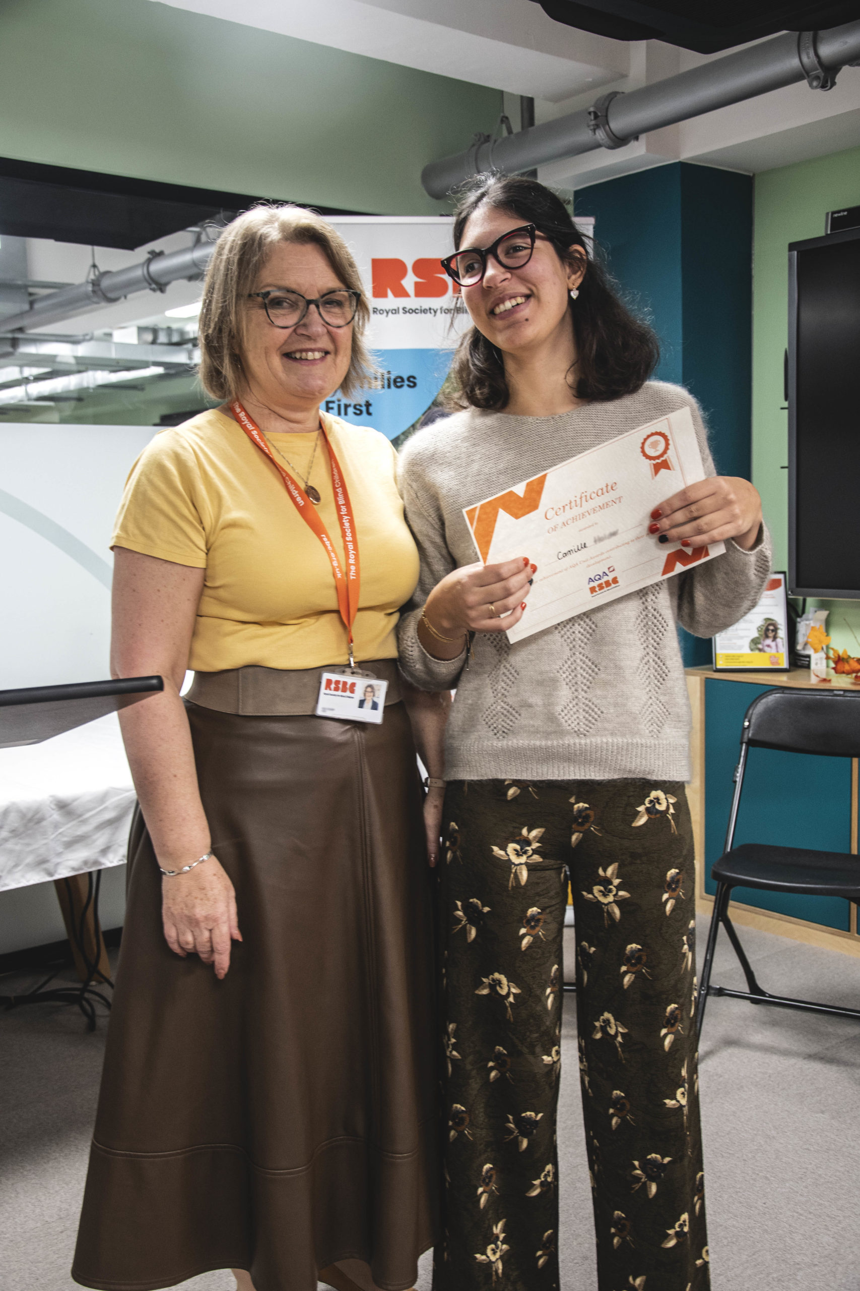 A young woman receiving a certificate standing up next a woman