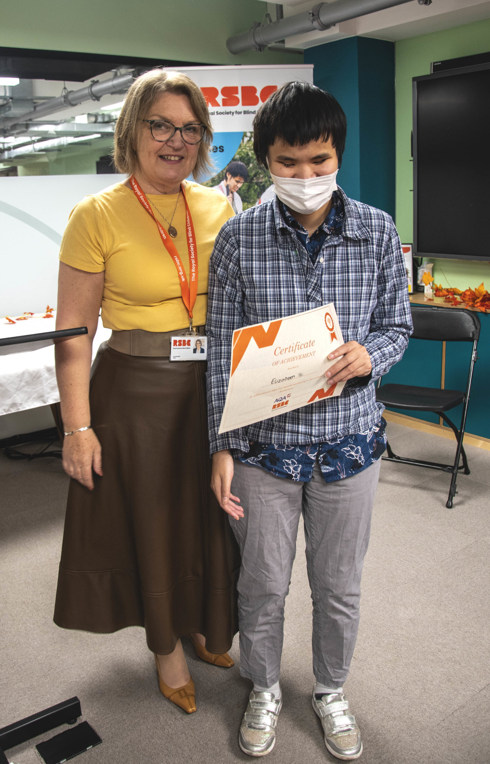 A young woman receiving a certificate standing up next a woman