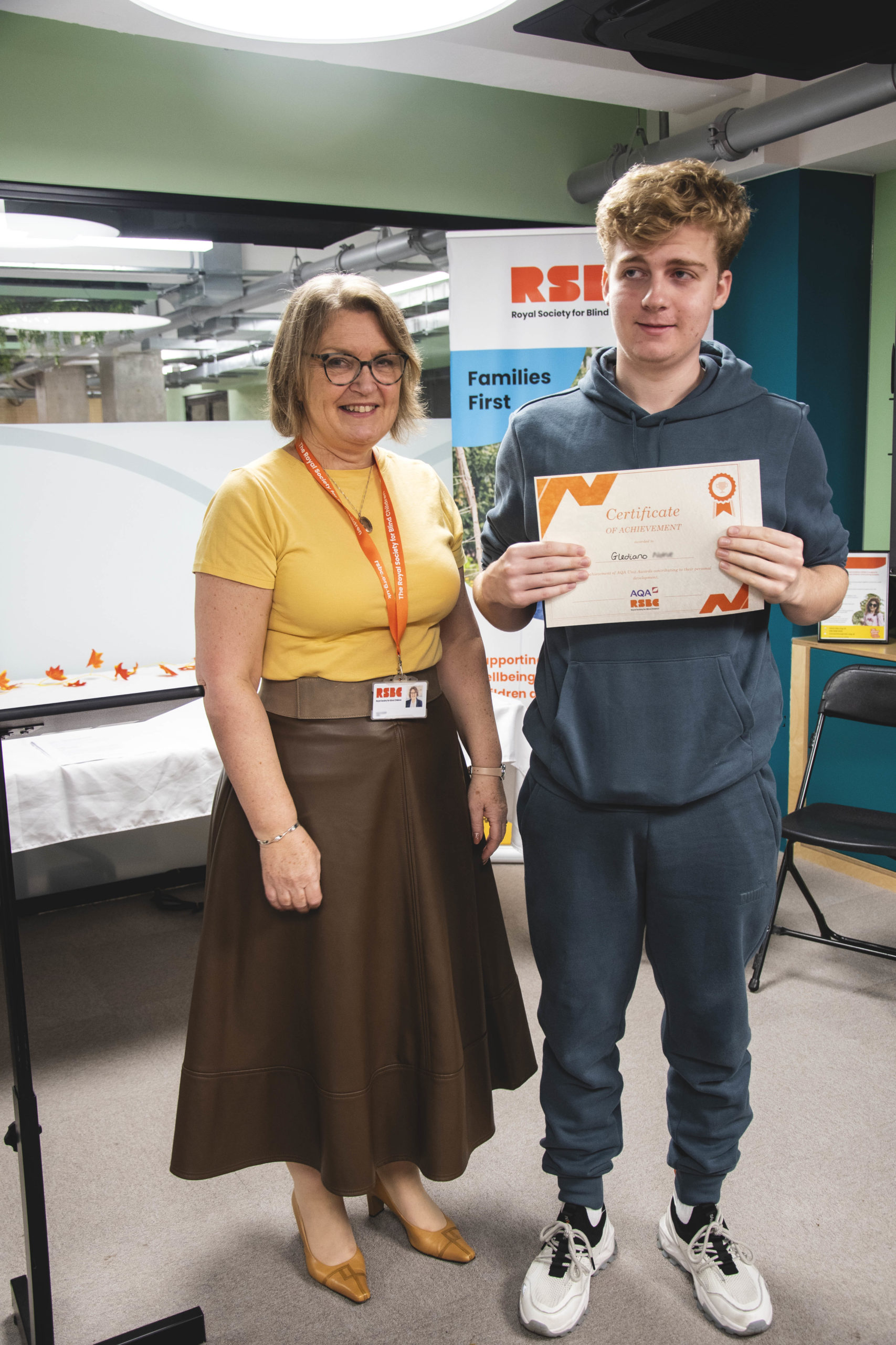 A young man receiving a certificate standing up next a woman