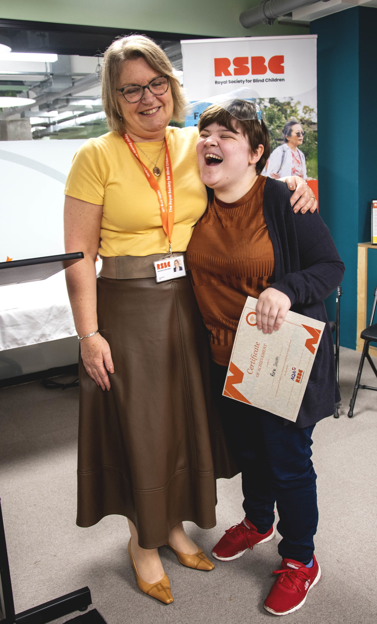 A young woman receiving a certificate standing up next a woman