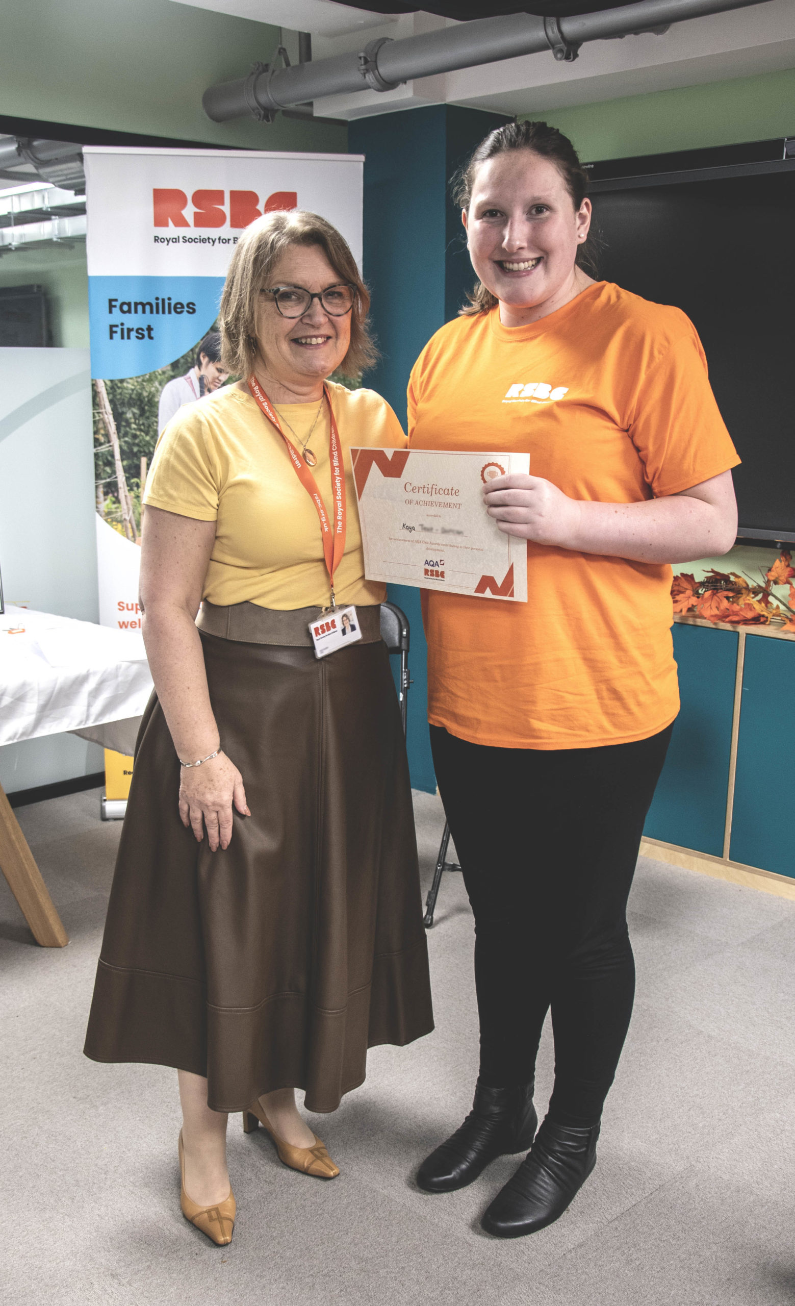 A young woman receiving a certificate standing up next a woman