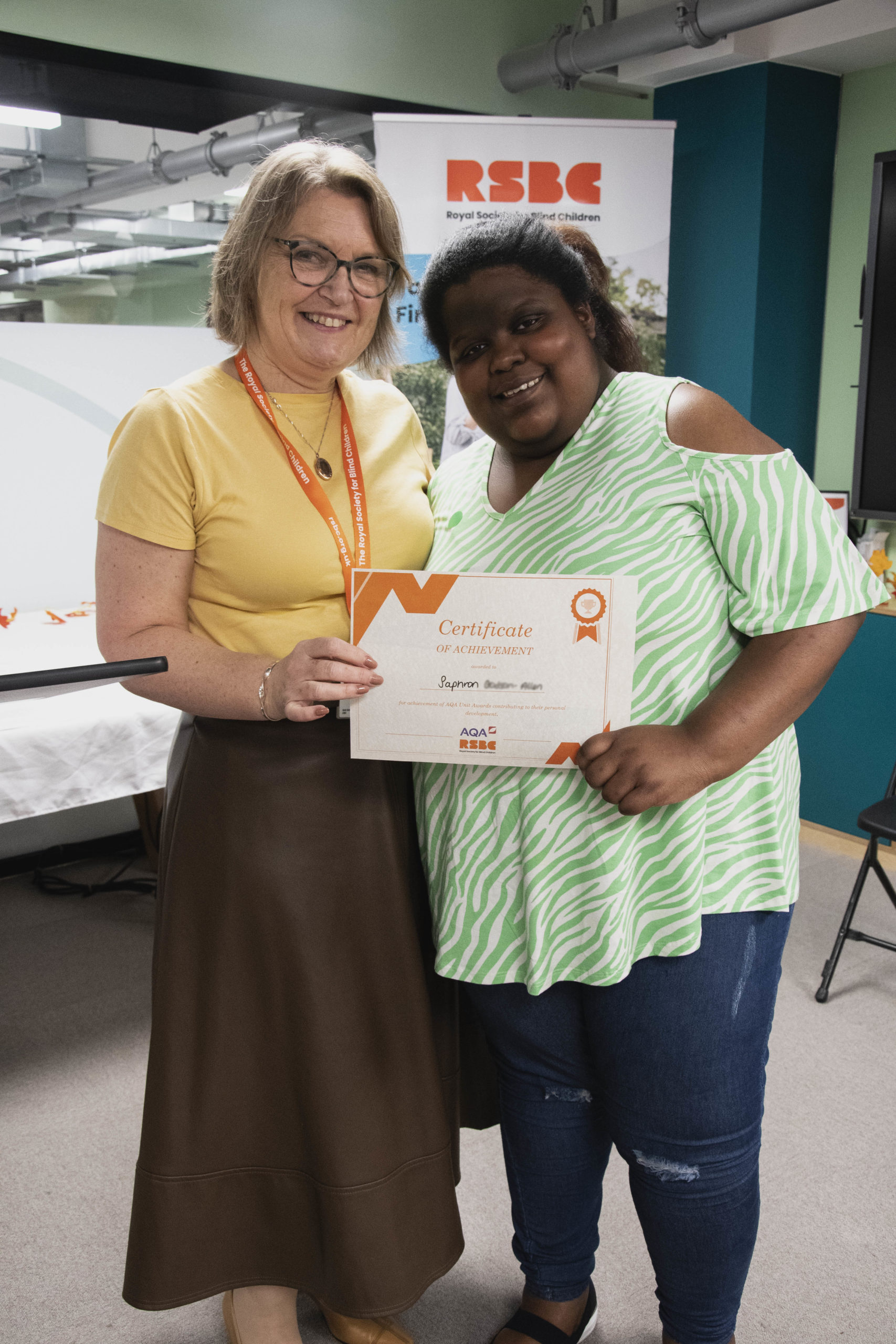 A young woman receiving a certificate standing up next a woman