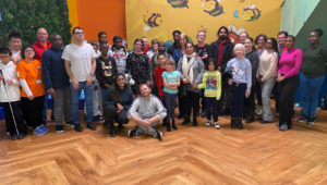 A group of people standing up in the Atrium of the Life Without Limits Centre