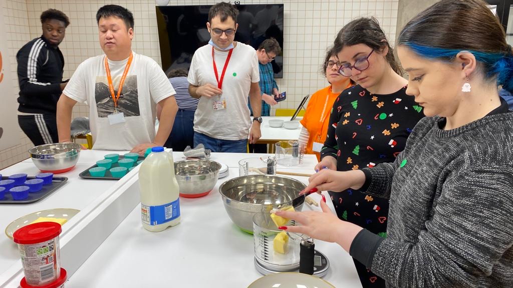 A group of people gathered in a kitchen to bake cupcakes