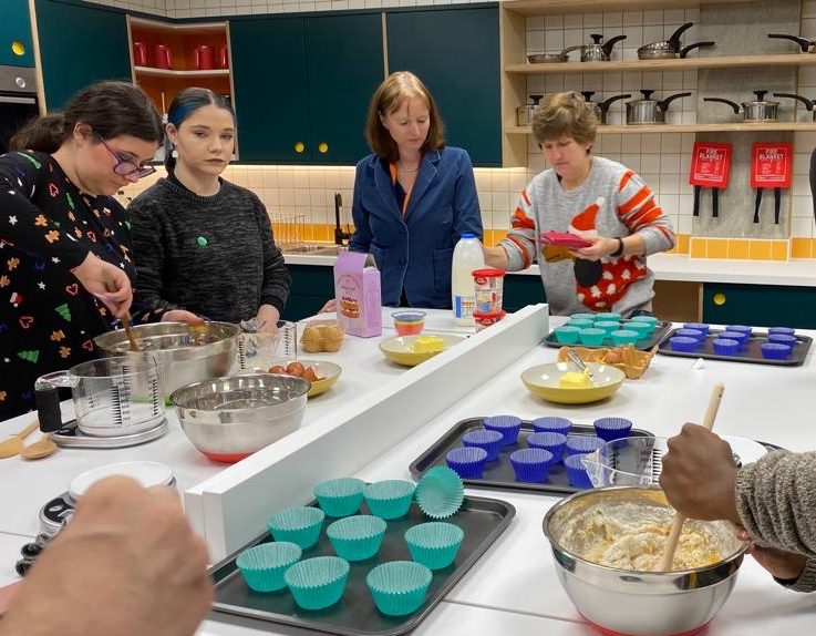 A group of people making cupcakes in a kitchen