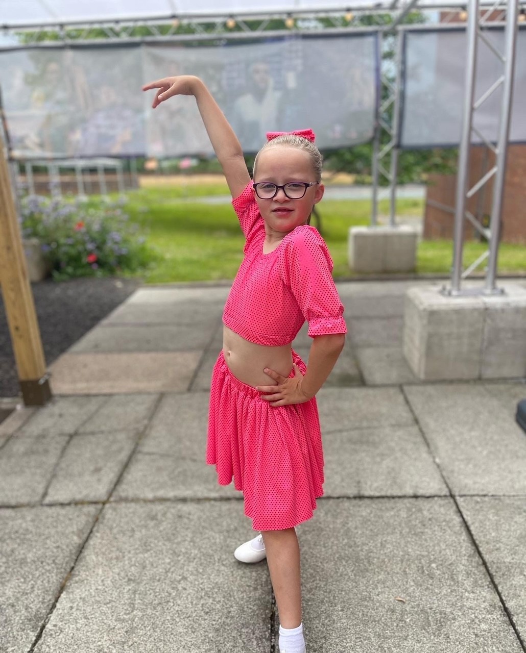 A young girl posing in a pink outfit and looking confident