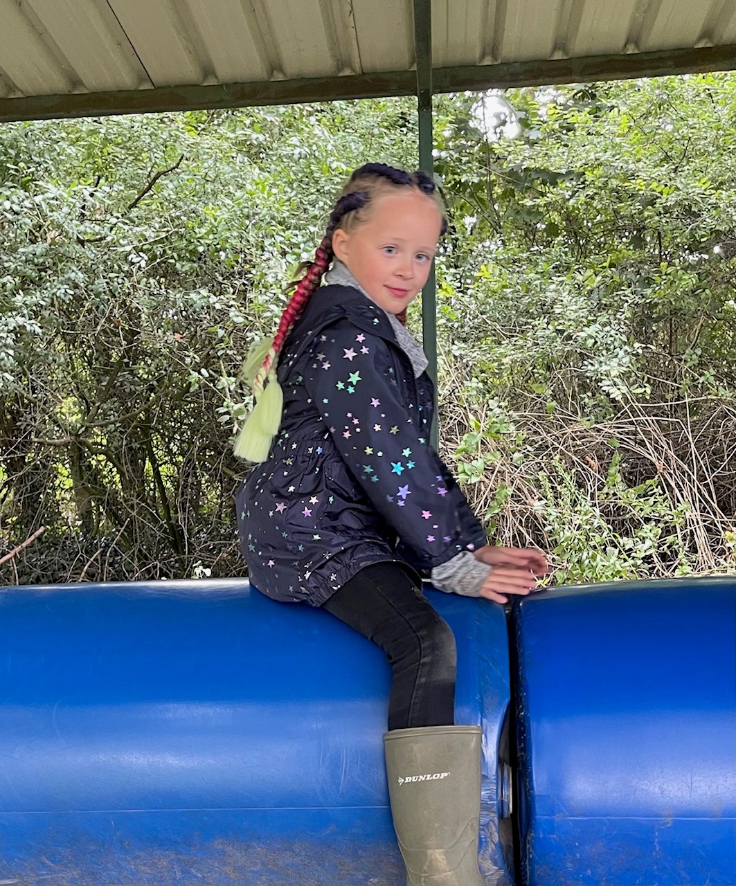 A young girl sitting on a big foam roller designed for kids's entertainment