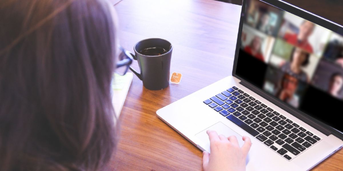 A woman sitting in front of a laptop and talking to several people online