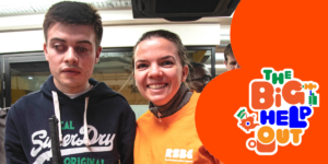 A photo of a young vision impaired young person next to an RSBC volunteer with a red design on the right which includes "The Big Help Out" logo.