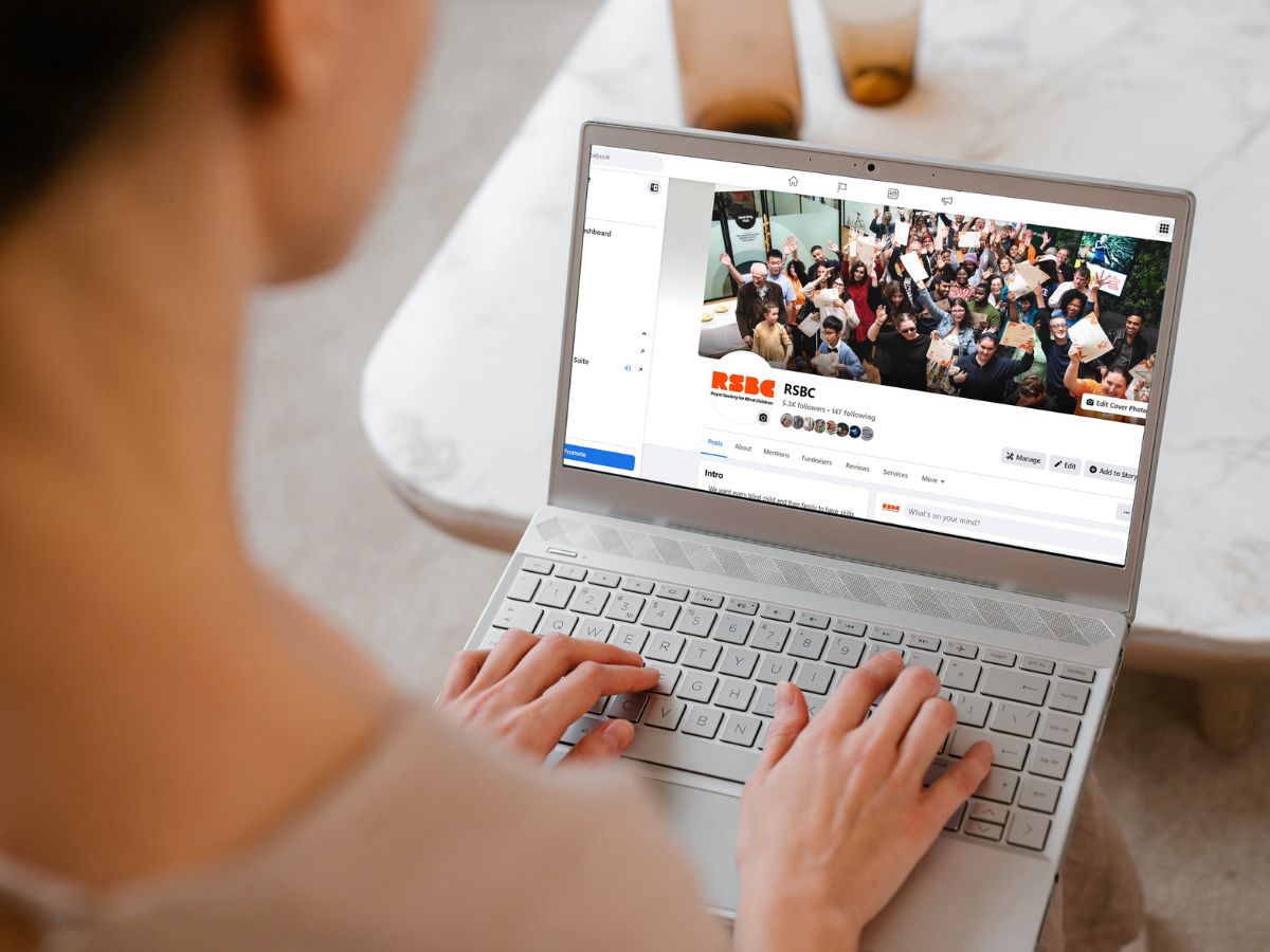 A person typing on a laptop with a screen showing the RSBC Connecting Parents Facebook Group