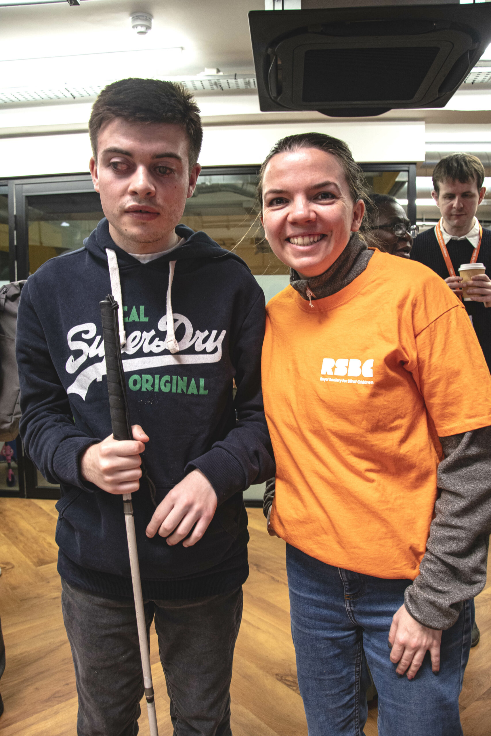 A young person with a cane next to an RSBC volunteer