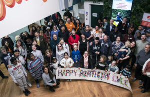 A group of people gathered in the RSBC Life Wihtout Limits Centre (LWLC). They are holdind a banner that says "Happy Birthday LWLC"