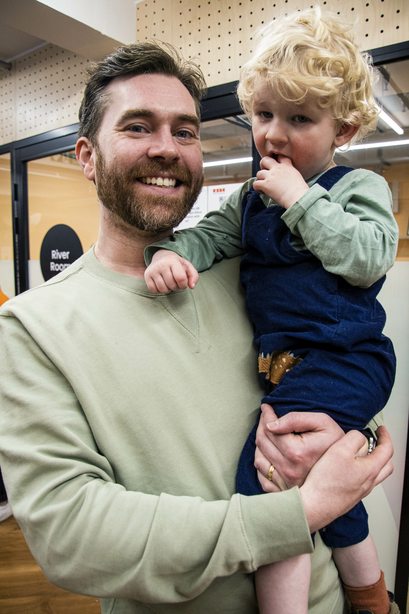 A dad standing up and holding his son