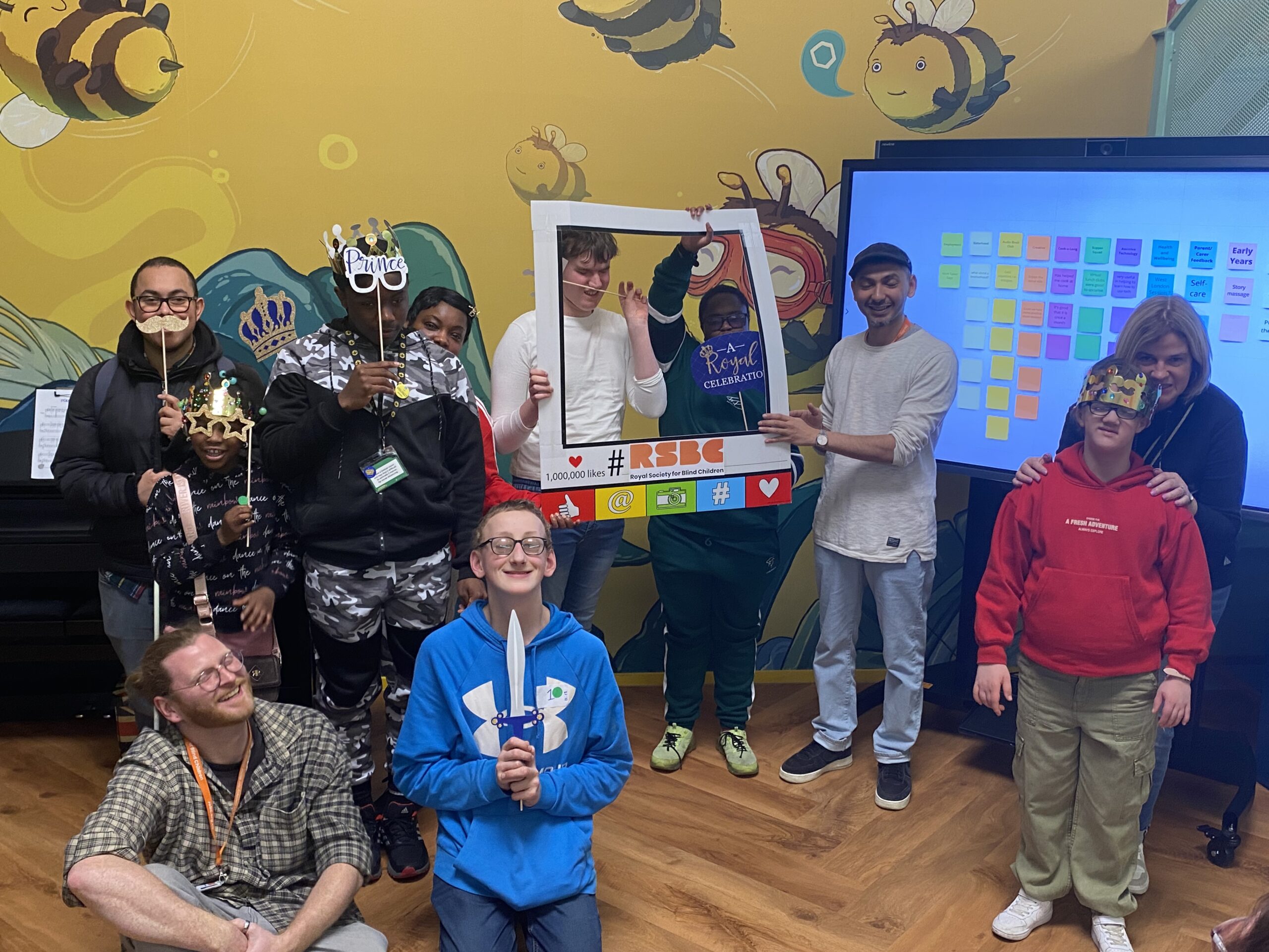 A group of people smiling with some of them holding royal themed accessories