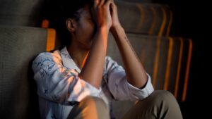 A young woman sat on the floor looking stressed