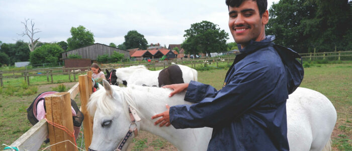 A young person smiling next to a horse