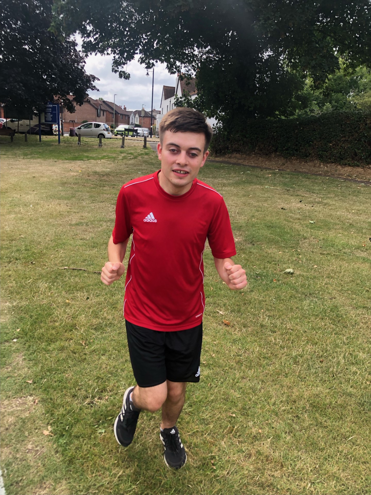 A young man in a red shirt and black shorts