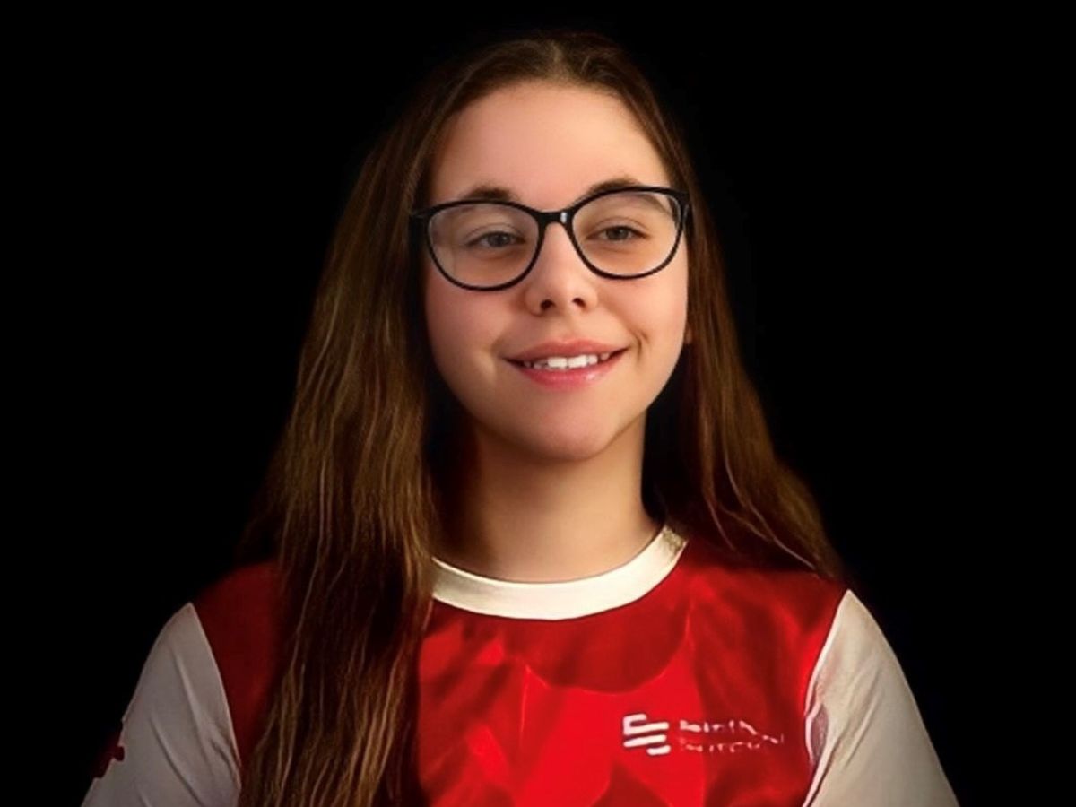 A smiling girl with brown hair, black glasses and a red and white t-shirt