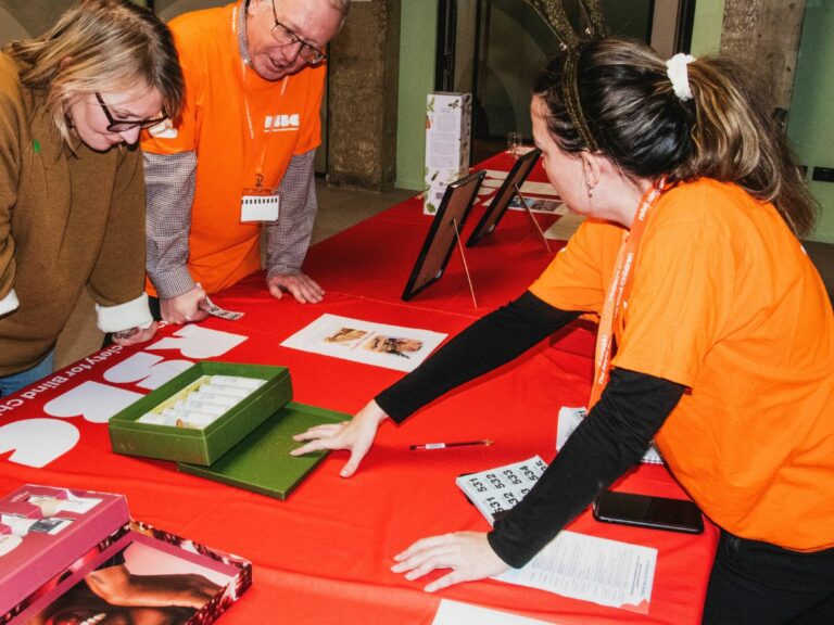 A group of people standing around a table and wearing orange RSBC volunteer t-shirts.