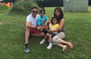 A photo of a family sitting outside on the grass.