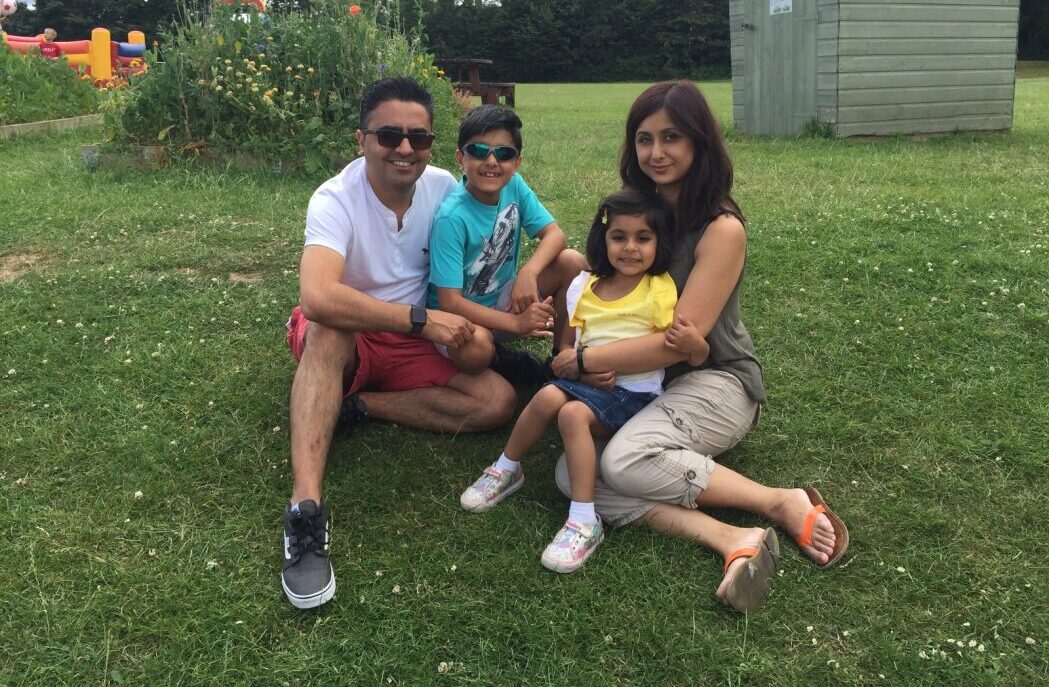 A photo of a family sitting outside on the grass.