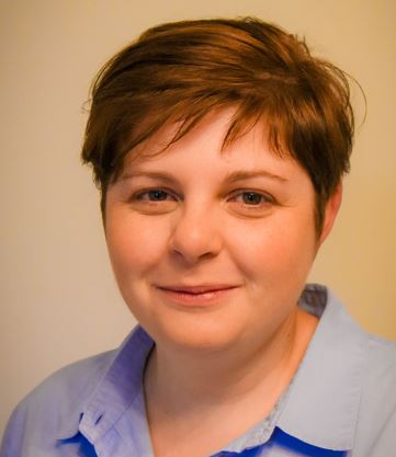 A headshot of Jeanette, a woman with a light skin colour and short brown hair. She wears a light blue collared shirt and is smiling.