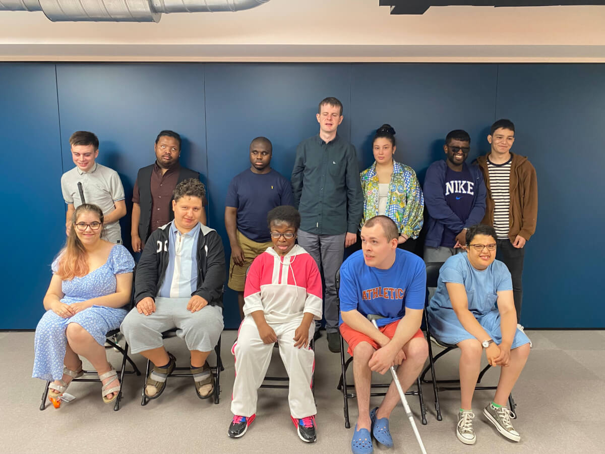 A group of Dorton College students stand and sit in front of a blue wall