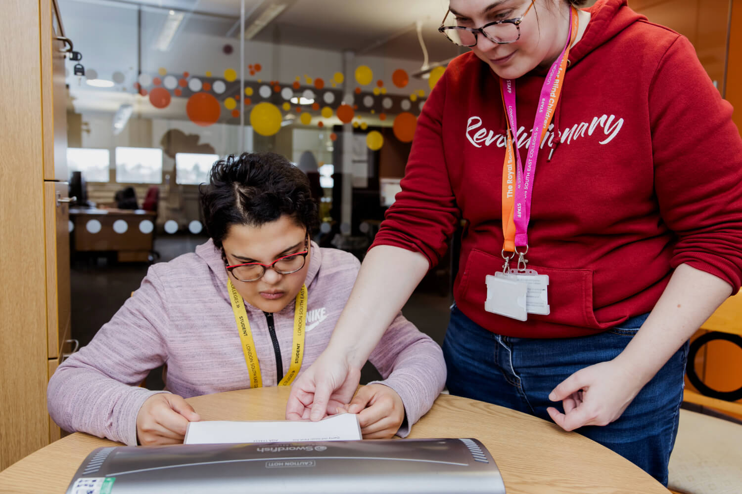 A student sits at a desk, being helped by an RSBC staff member