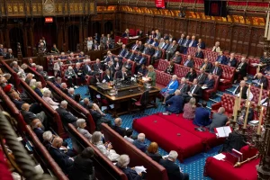 Members of Parliament sat down in the House of Lords (a large, stately and and old fashioned looking room, with leather pews). The room is 90% full.