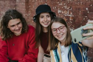 A group of teenage friends(1 male and 2 females) taking a selfie and smiling