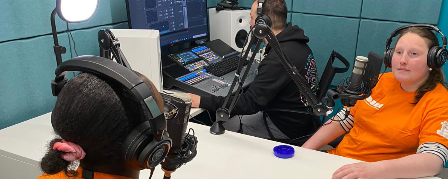 Three people recording a podcast in a media room.