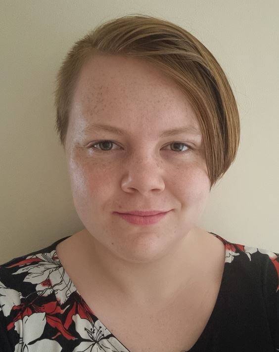 Headshot of Jae, a Learning Support Assistant at RSBC Dorton College. Jae is a light-skinned woman with short blonde hair. Jae is wearing a black and floral print shirt and smiling at the camera.