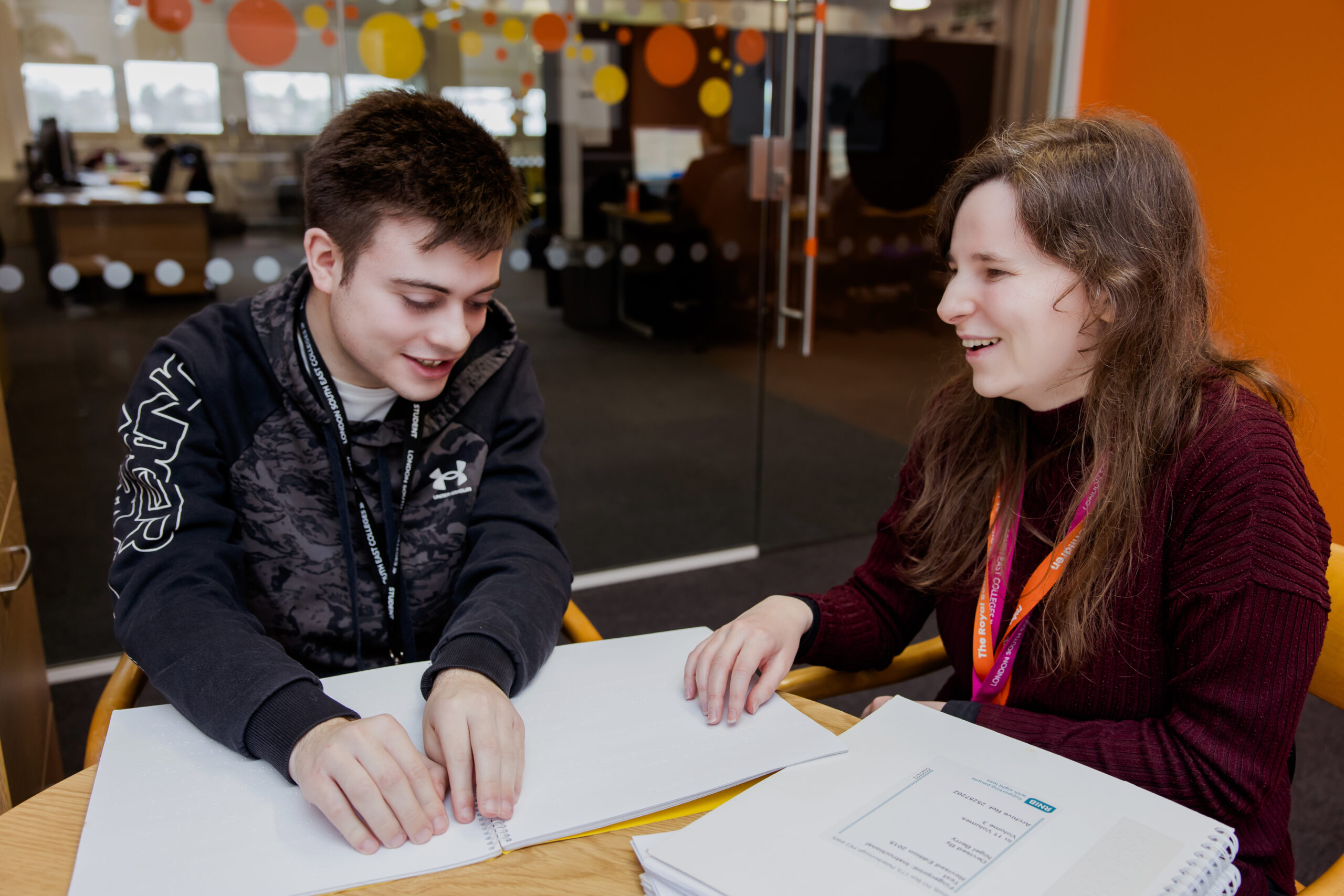 A Dorton College student and tutor working together on a braille excerise. The pair are smiling and laughing together.