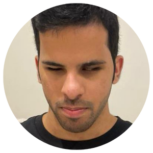 A head and shoulders image of Mohammed, a medium skinned young person with dark hair and stubble, wears a black T shirt as he looks downwards with a serious expression.