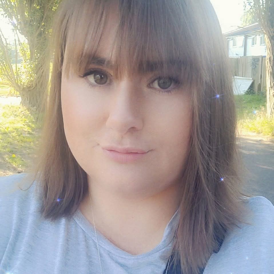 A light-skinned women with light brown straight hair and hazel green eyes wearing a white t-shirt.